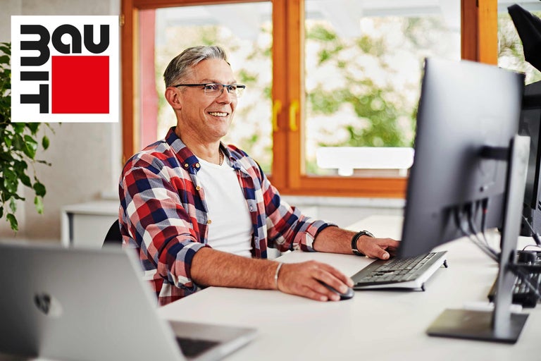 Mann arbeitet am Computer im Homeoffice. Baumit Logo.