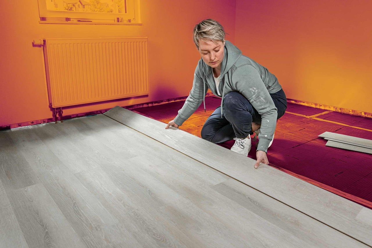 Frau verlegt Laminatboden im Innenraum