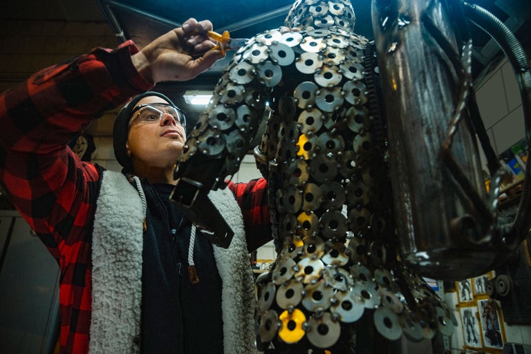 Ein Mann bearbeitet eine Metallskulptur in einer Werkstatt.