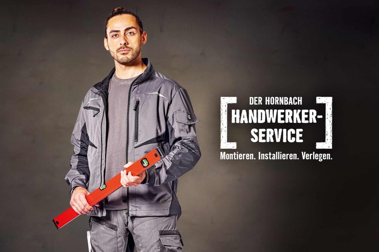 Ein Handwerker in Arbeitskleidung hält eine Wasserwaage in der Hand. Im Hintergrund steht der Hornbach Handwerkerservice.