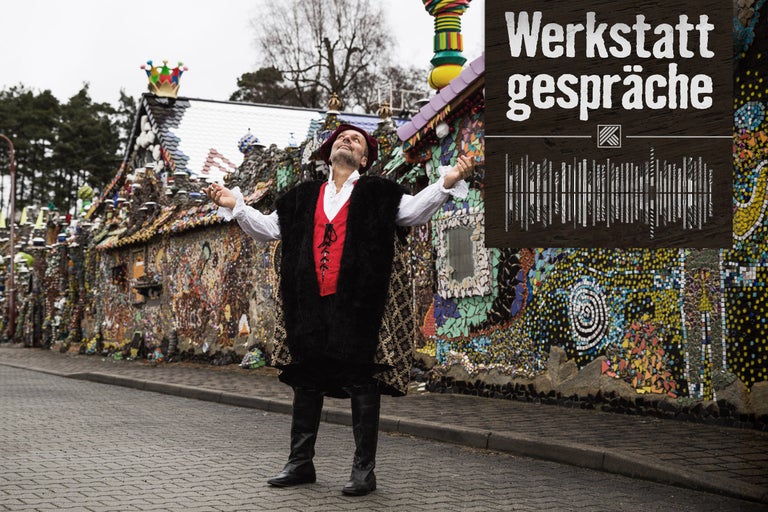 Ein Mann steht vor einem mit Mosaiken verzierten Gebäude mit dem Text Werkstatt Gespräche.
