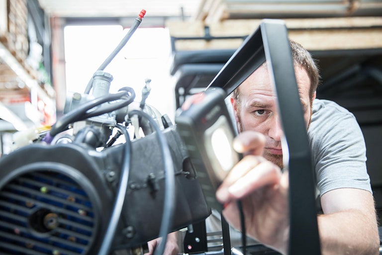 Ein Mann beleuchtet einen Motorblock mit einer Arbeitsleuchte
