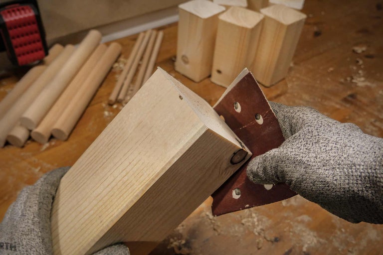 Holzbein wird mit Schleifpapier bearbeitet