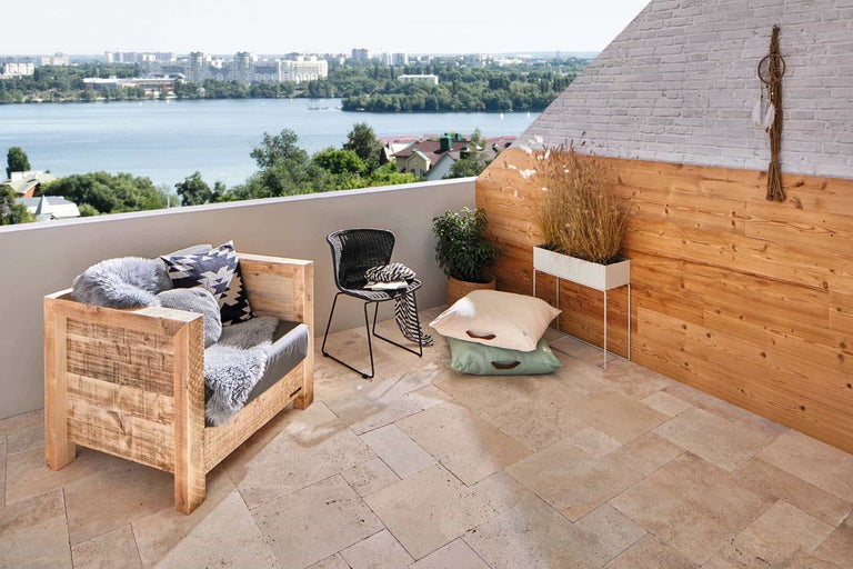 Balkon mit Holzmöbeln, Stuhl, Kissen und Blick auf einen See