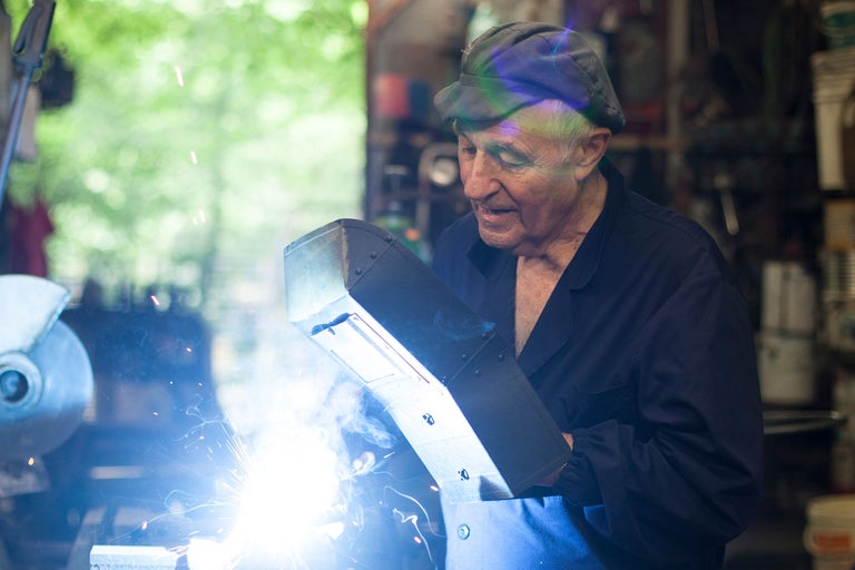 Ein Mann schweißt mit einer Schweißmaske in einer Werkstatt.