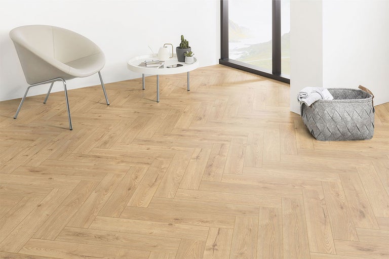 Heller Raum mit Fischgrätparkett, Sessel, Tisch und Korb