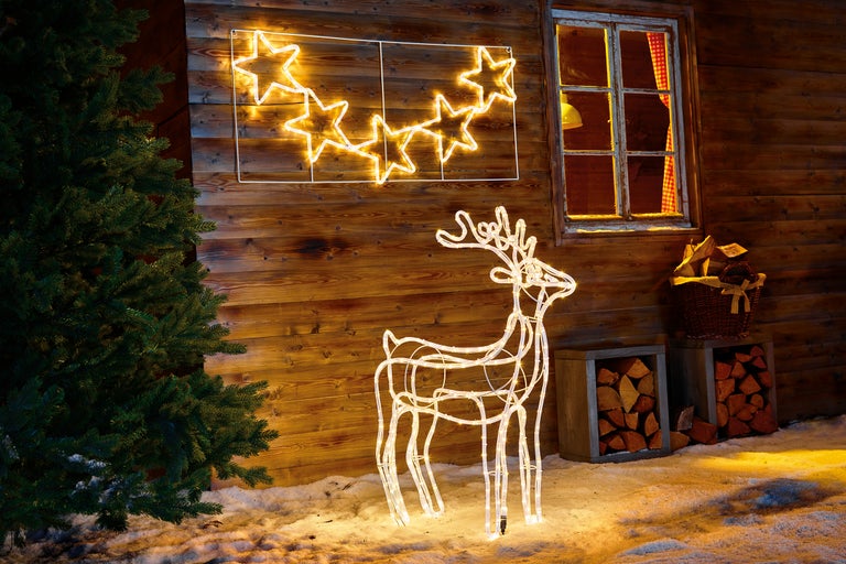 Dekoratives Arrangement mit beleuchtetem Sternen- und Rentier-Motiv vor einer Holzwand