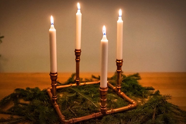 Adventskranz mit vier brennenden Kerzen auf Tannenzweigen