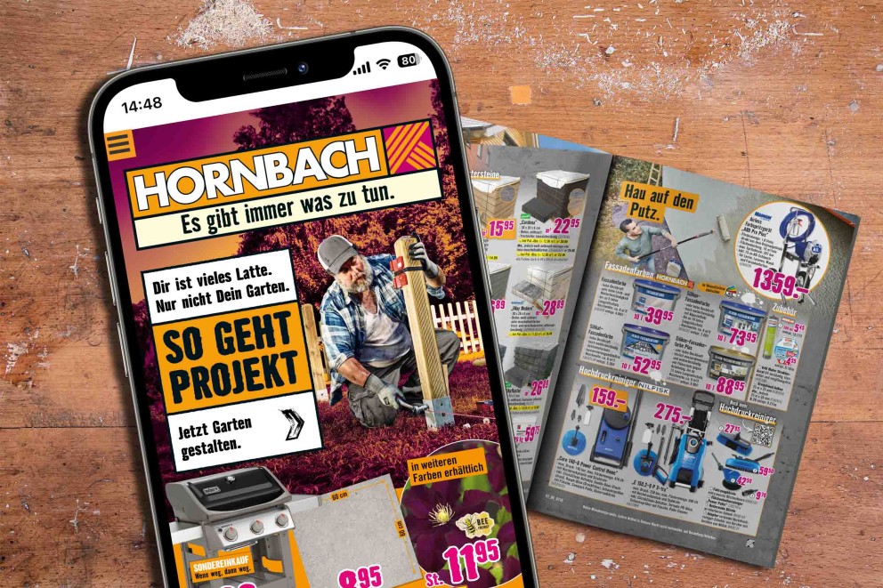 Smartphone zeigt Hornbach Werbung neben Produktkatalog auf Holztisch