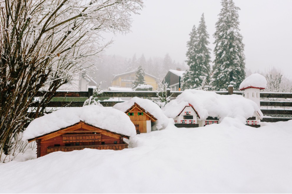 Verschneite Landschaft mit Holzhausmodellen, die fast ganz im Schnee versunken sind. Verschneite Landschaft mit Holzhausmodellen, die fast ganz im Schnee versunken sind.