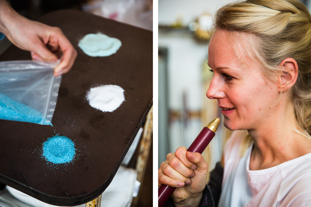 Autorin Birte Schmidt verstreut gemeinsam mit Sabine Putbrese, Leiterin des Workshops am Glasofen, zerbröseltes Farbglas in Weiß und zwei Blautönen auf einem Metalltisch
