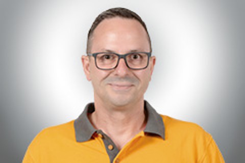 Porträt eines Mannes mit Brille in einem gelben Poloshirt