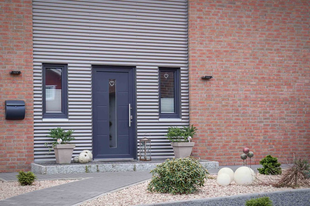 Fassade eines Hauses mit Haustür, Fenstern, Briefkasten und Außenbeleuchtung