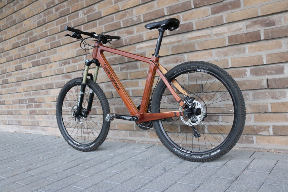 Cycle Ligneos Fahrrad mit Holzrahmen vor einer Ziegelwand
