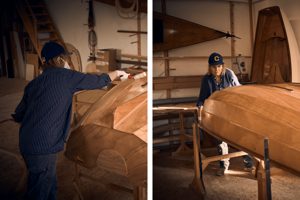 Zwei Personen arbeiten in einer Werkstatt an Holzbooten.
