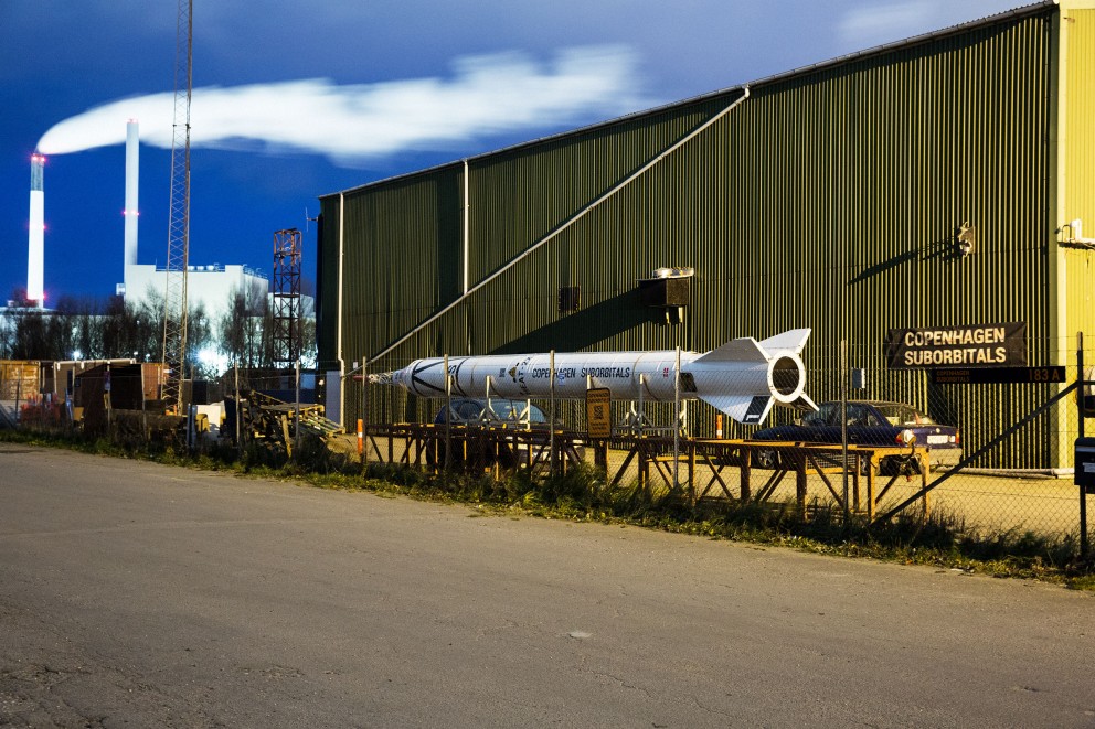 Vor der Werkhalle der Suborbitals nahe des Hafens von Kopenhagen ist ein altes Raketenmodell aufgebaut. In der Halle dahinter schrauben die Copenhagen Suborbitals in Kopenhagen an ihrem Traum Vor der Werkhalle der Suborbitals nahe des Hafens von Kopenhagen ist ein altes Raketenmodell aufgebaut. In der Halle dahinter schrauben die Copenhagen Suborbitals in Kopenhagen an ihrem Traum