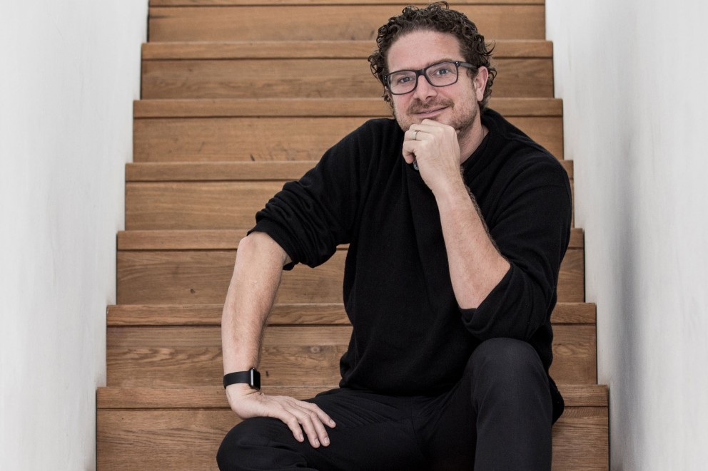 Mann mit Brille sitzt auf einer Holztreppe
