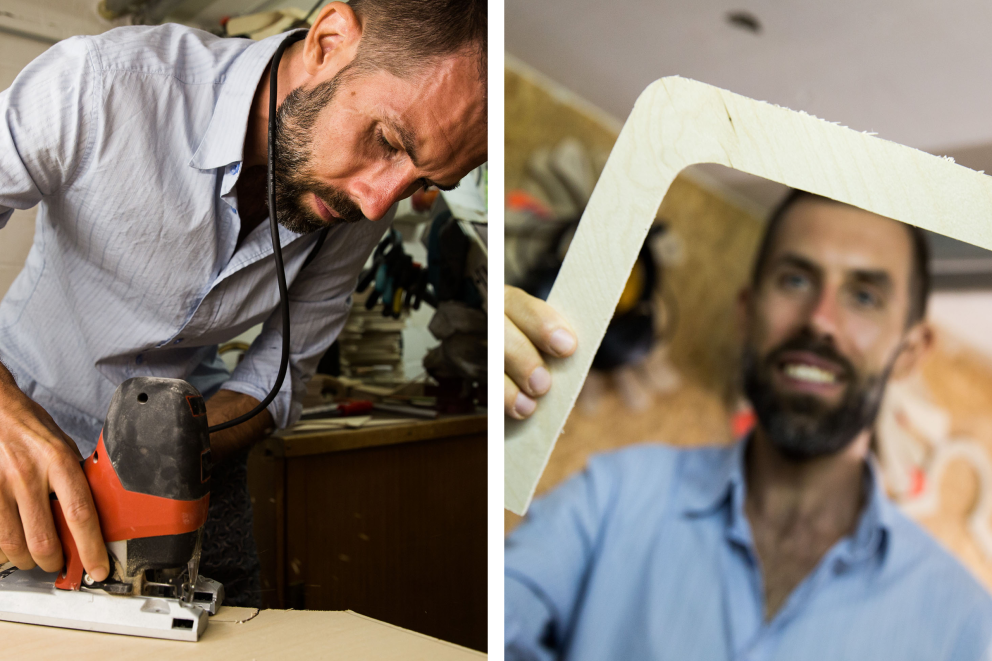 Ein Mann schneidet Holz mit einer Stichsäge, während ein anderer Mann ein gebogenes Holzstück hält.