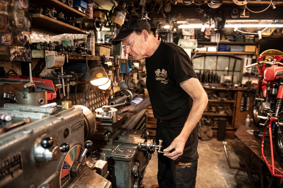 Mann arbeitet an Drehbank in Werkstatt mit Motorrad