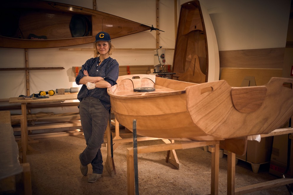 Werkstatt mit Frau und einem Holzboot im Bau