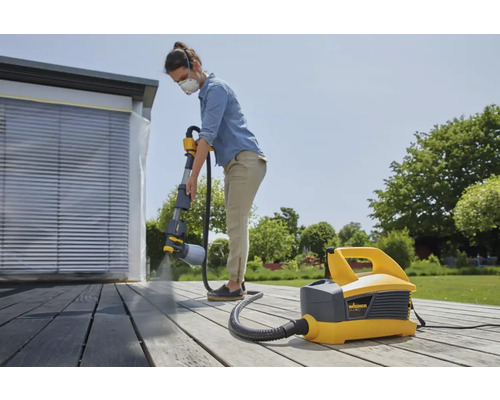 "Frau streicht mit Farbsprühsystem die Terrasse
