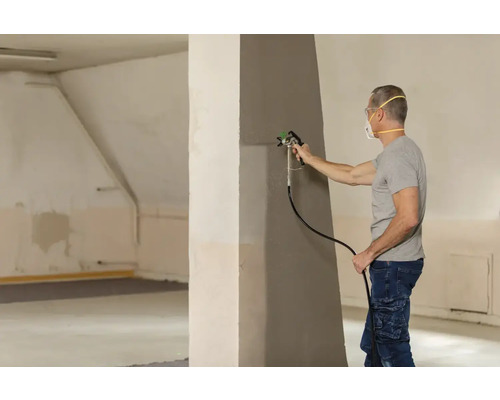 Mann streicht Wand mit Farbspritzgerät
