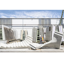 Außenaufnahme einer Betonfertigtreppe auf einer Baustelle mit Bauarbeiter und Fertigbetonwänden