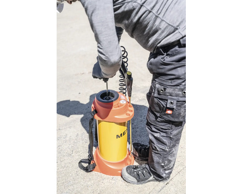 Handwerker befüllt Mörtelspritzgerät mit Rucksackfunktion