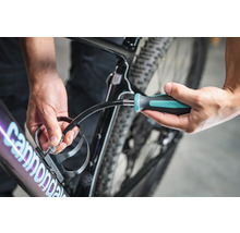 Eine Person befestigt einen Getränkehalter mit einem Schraubendreher an einem Fahrrad.