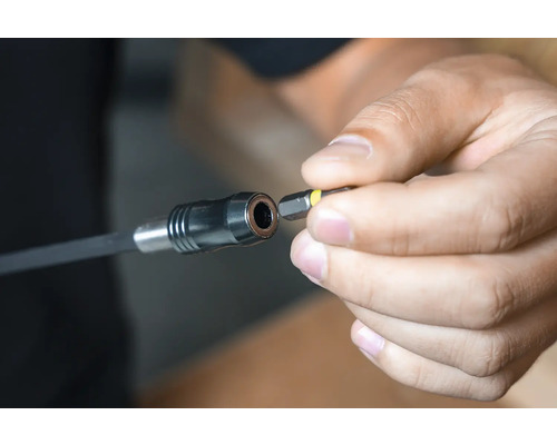 Eine Person setzt ein Schrauberbit in eine Bithalterverlängerung ein.