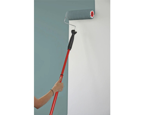 Farbe wird mit Farbroller und Teleskopstiel auf eine Wand aufgetragen.