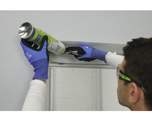Person trägt Schutzbrille und Handschuhe und verwendet Bauschaum zur Installation einer Duschkabine