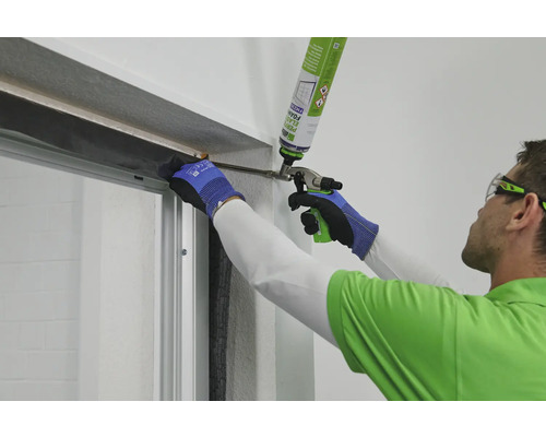 Mann dichtet Fenster mit Bauschaum ab