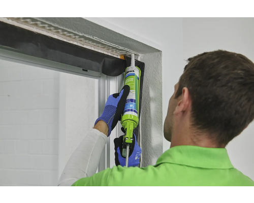 Ein Mann dichtet ein Fenster mit Dichtmasse ab.