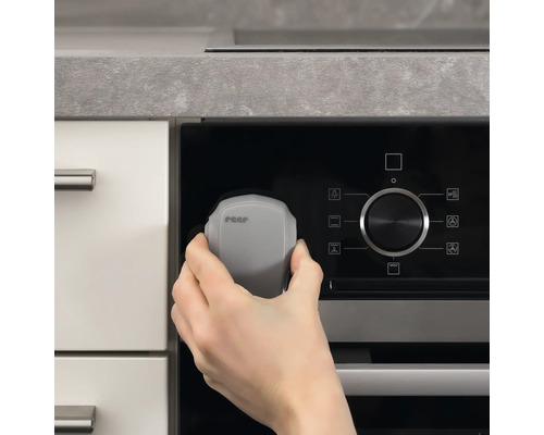 Eine Hand befestigt eine Reer Herdsicherung an einem Herd.