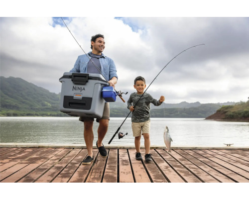 Vater und Sohn angeln mit einer Kühlbox am See