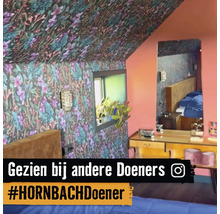 Schlafzimmer mit floral gemusterter Tapete an Wänden und Decke, Fenster, Spiegel und Kommode.