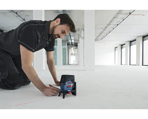 Handwerker markiert mit einem Linienlaser einen Boden in einem Rohbau