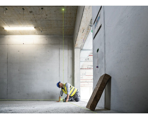 Ein Bauarbeiter verwendet einen Laser zur Ausrichtung in einem Rohbau.
