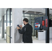 Handwerker markiert mit einem Laser-Entfernungsmesser eine Wand