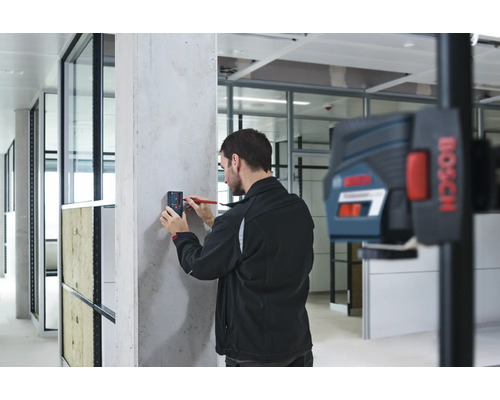 Handwerker markiert mit einem Laser-Entfernungsmesser eine Wand