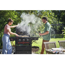 Frau und Mann grillen mit einem Gas- und Kohlegrill im Garten.