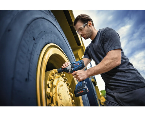 Ein Mann benutzt einen Akku-Drehschlagschrauber an einem großen Reifen eines Nutzfahrzeugs.