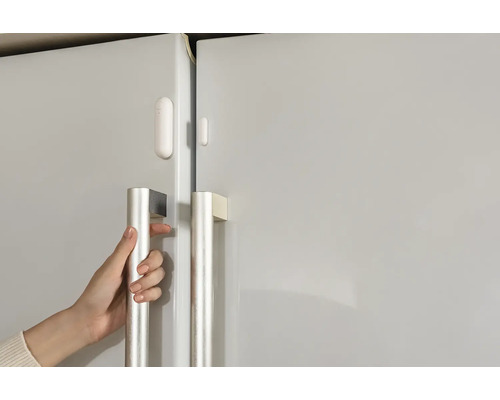 Nahaufnahme einer Hand, die einen Kühlschrank öffnet, ausgestattet mit einem Türsensor.