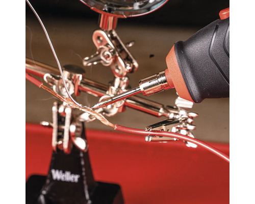 Löten von Kabeln mit Lötkolben in Halterung mit Lupe.