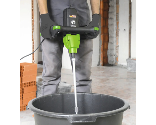 Person verwendet einen Mörtelrührer in einem Eimer.