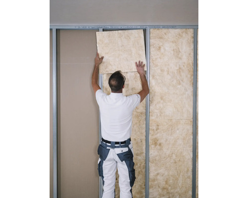 Ein Mann montiert eine Dämmplatte an einer Wand.