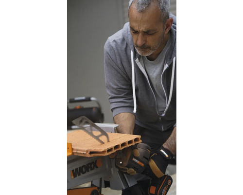 Ein Mann sägt einen Ziegelstein mit einer Tischsäge von Worx.