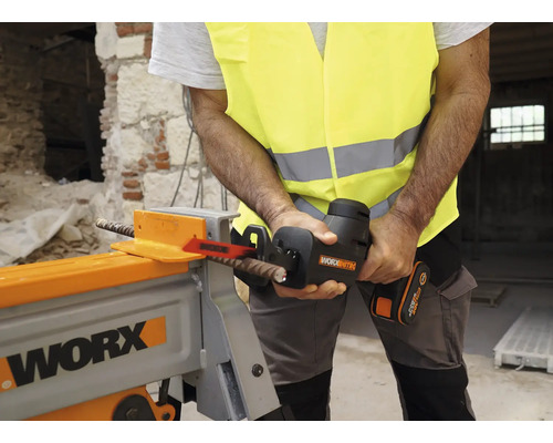 Ein Mann in Sicherheitsweste schneidet mit einer Akku-Säbelsäge ein Armierungseisen in einer Werkstatt.