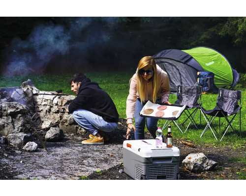 Zwei Personen campen mit Zelt, Kühlbox, Campingstühlen und Grill